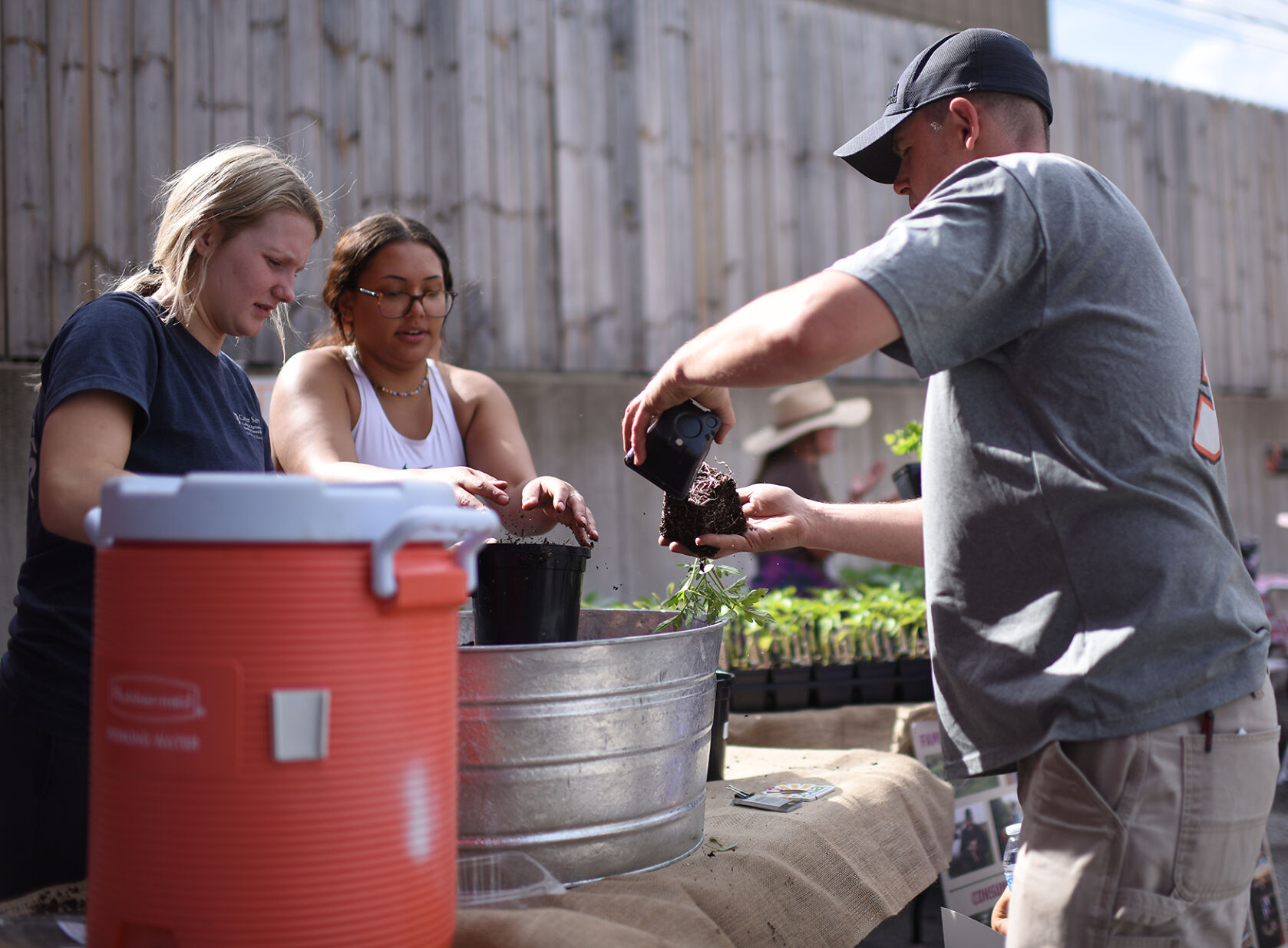 Tierney Lonberger, left, and Avery Cooper help Scott Jamison replant the plant of his choosing on Thursday at the Missouri Rural Crisis Center in Columbia.